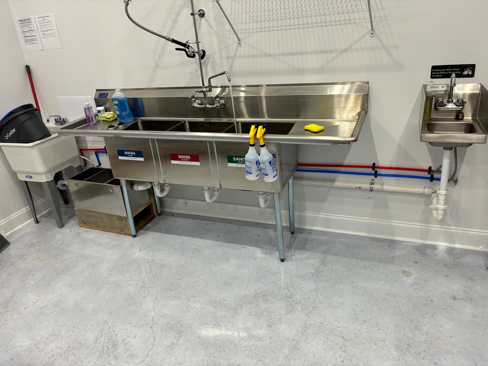 Commercial three-compartment sink installation with wash, rinse, and sanitize stations