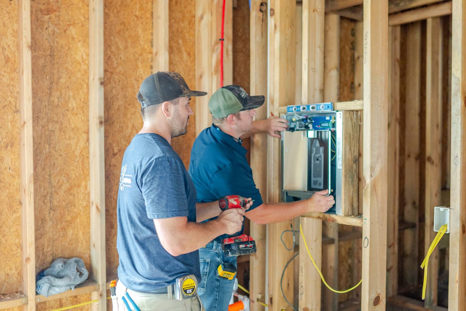 Two Prestige Plumbing crew members installing equipment in a new home