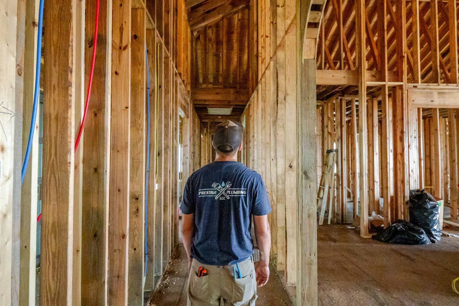 Prestige Plumbing plumber walking through a framed new home during rough-in