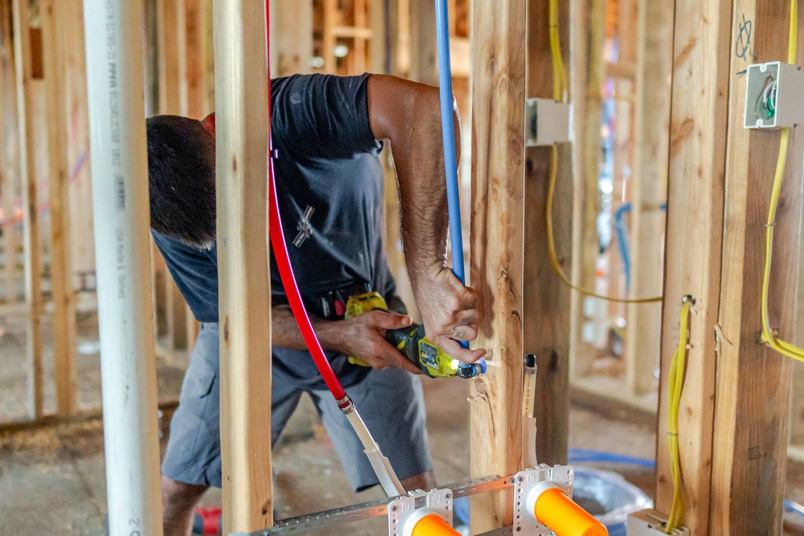 Prestige Plumbing plumber drilling framing to run PEX supply lines in a new home